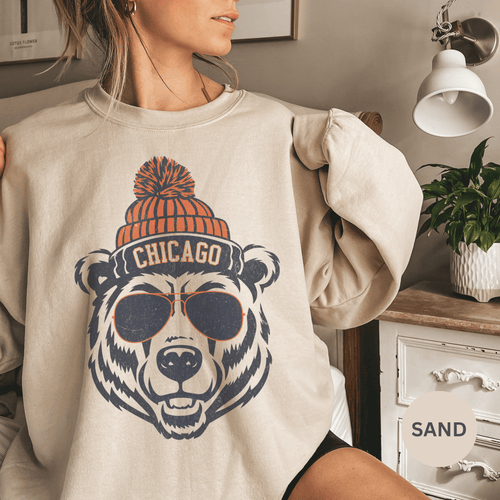 Person wearing a beige sweatshirt with a bear graphic and 'Chicago' text, indoors.