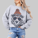 Person wearing a gray sweatshirt with a bear graphic and 'Chicago' text, sitting on a white surface.