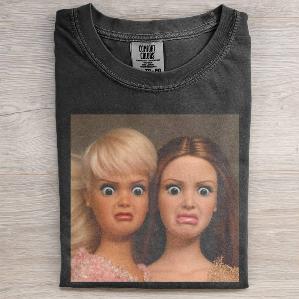 Black t-shirt with a graphic of two dolls on a wooden surface