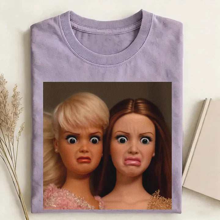 Folded purple t-shirt with a graphic of two dolls on a light background