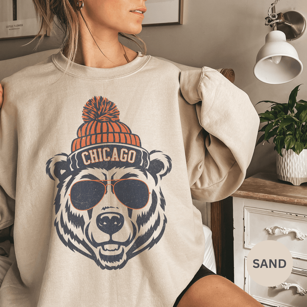Person wearing a beige sweatshirt with a bear graphic and 'Chicago' text, indoors.