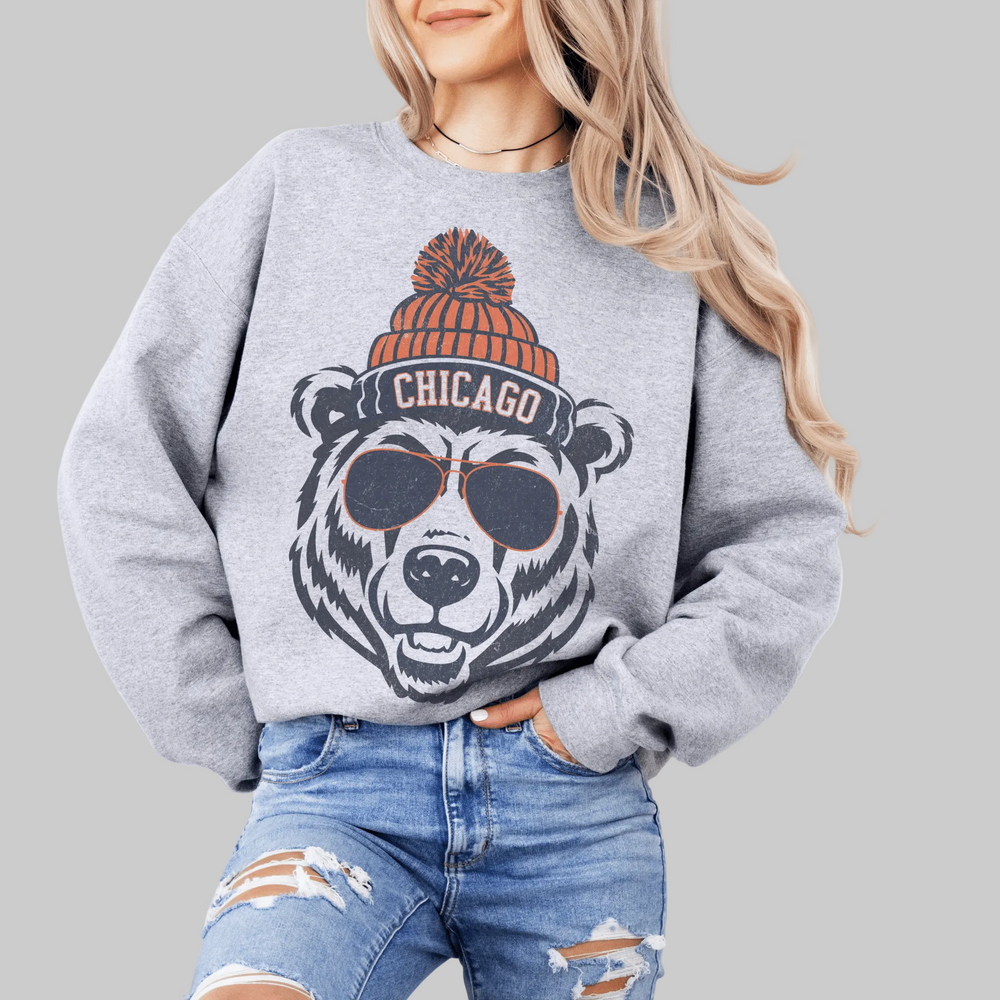 Person wearing a gray sweatshirt with a bear graphic and 'Chicago' text, sitting on a white surface.