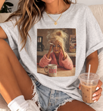 women wearing a funny  gray t-shirt with a graphic design of a woman with blonde hair and a coffee mug.
